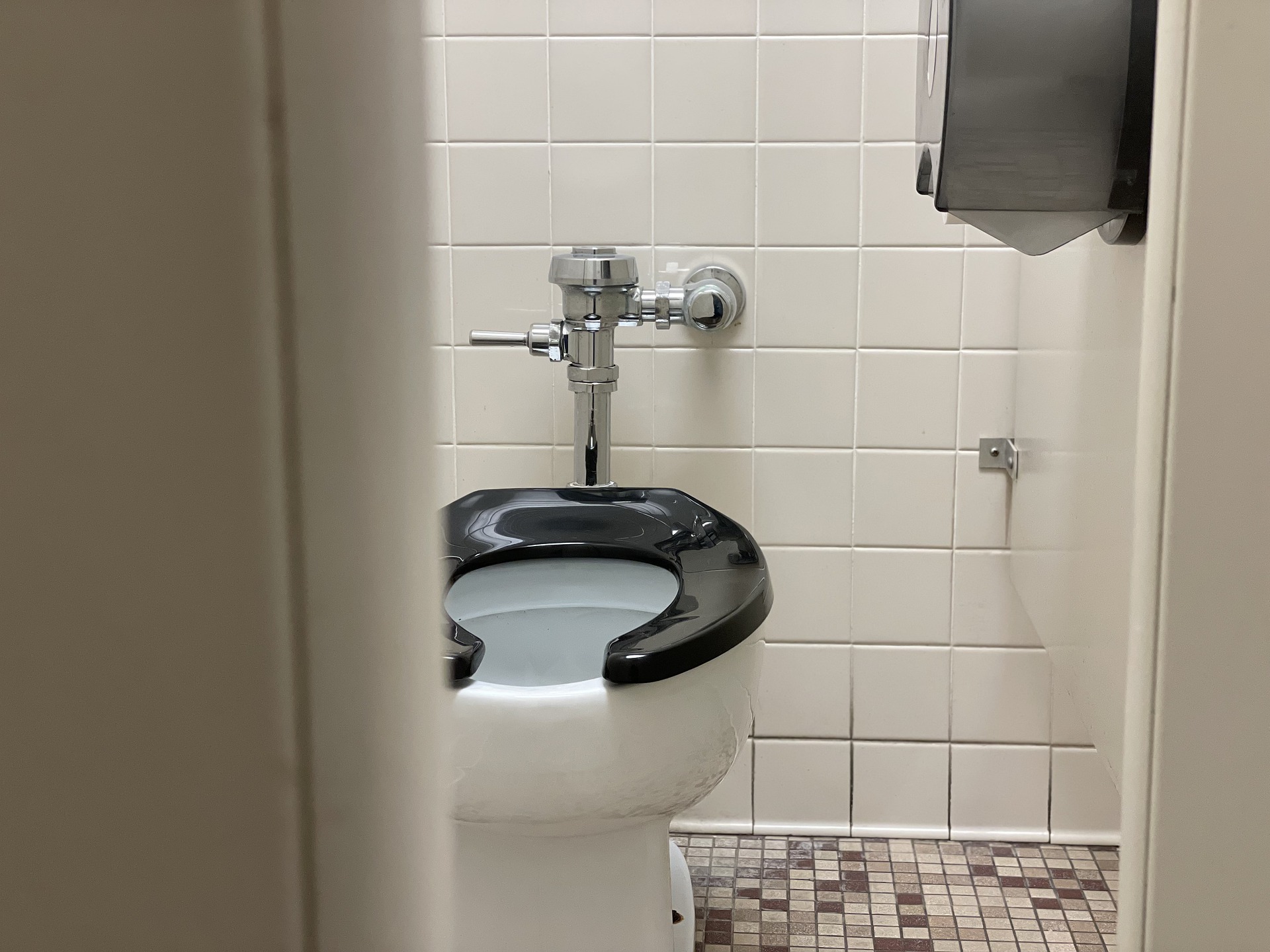 A picture of an ADA Toilet with tile on the walls.