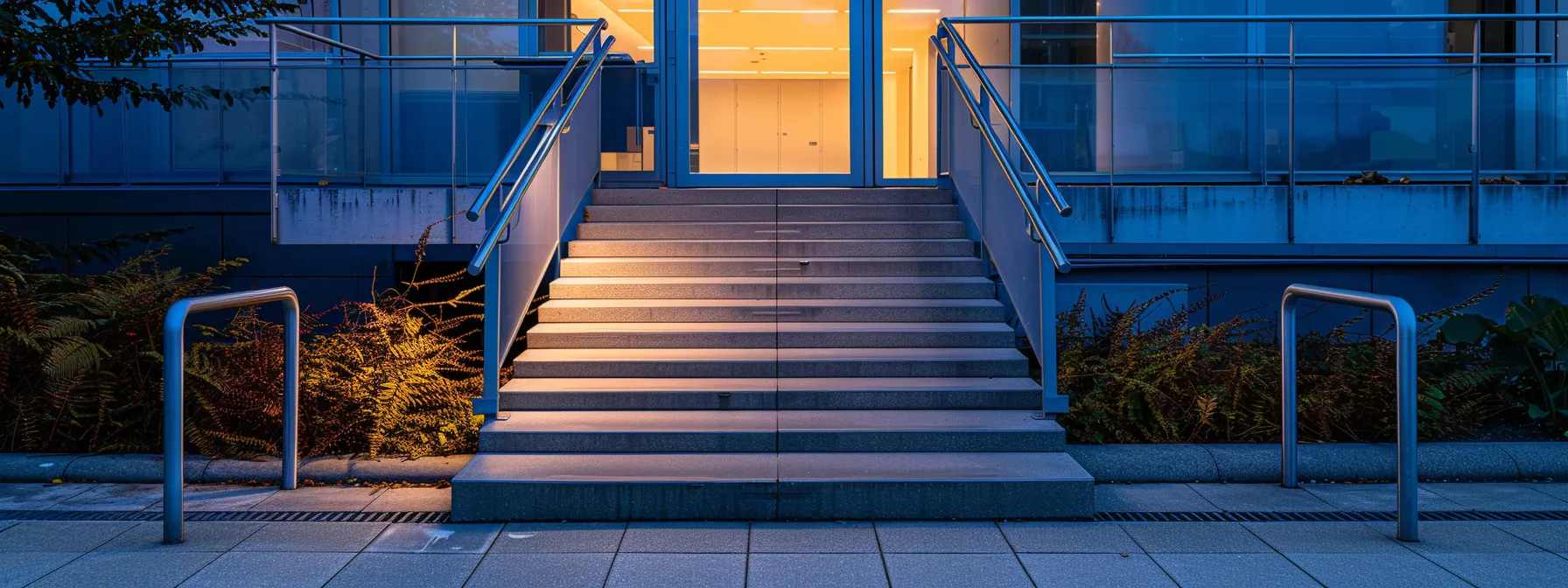 a wheelchair ramp leading up to a modern building entrance with handrails and clear signage.