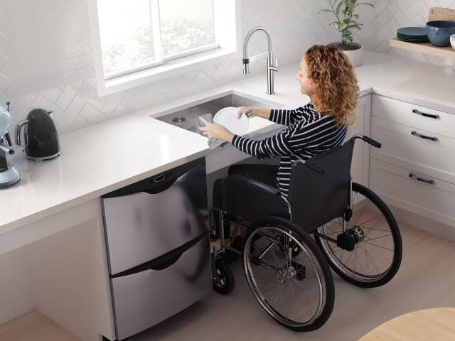 woman in the wheelchair washing dishes in the sink