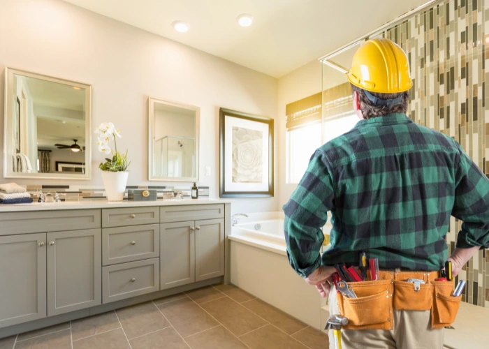 A man in a hard hat inspects a bathroom, highlighting ADA deficiencies in accessibility features.